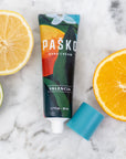 Pasko Valencia hand cream tube with sliced lemon, lime, and orange on a marble background