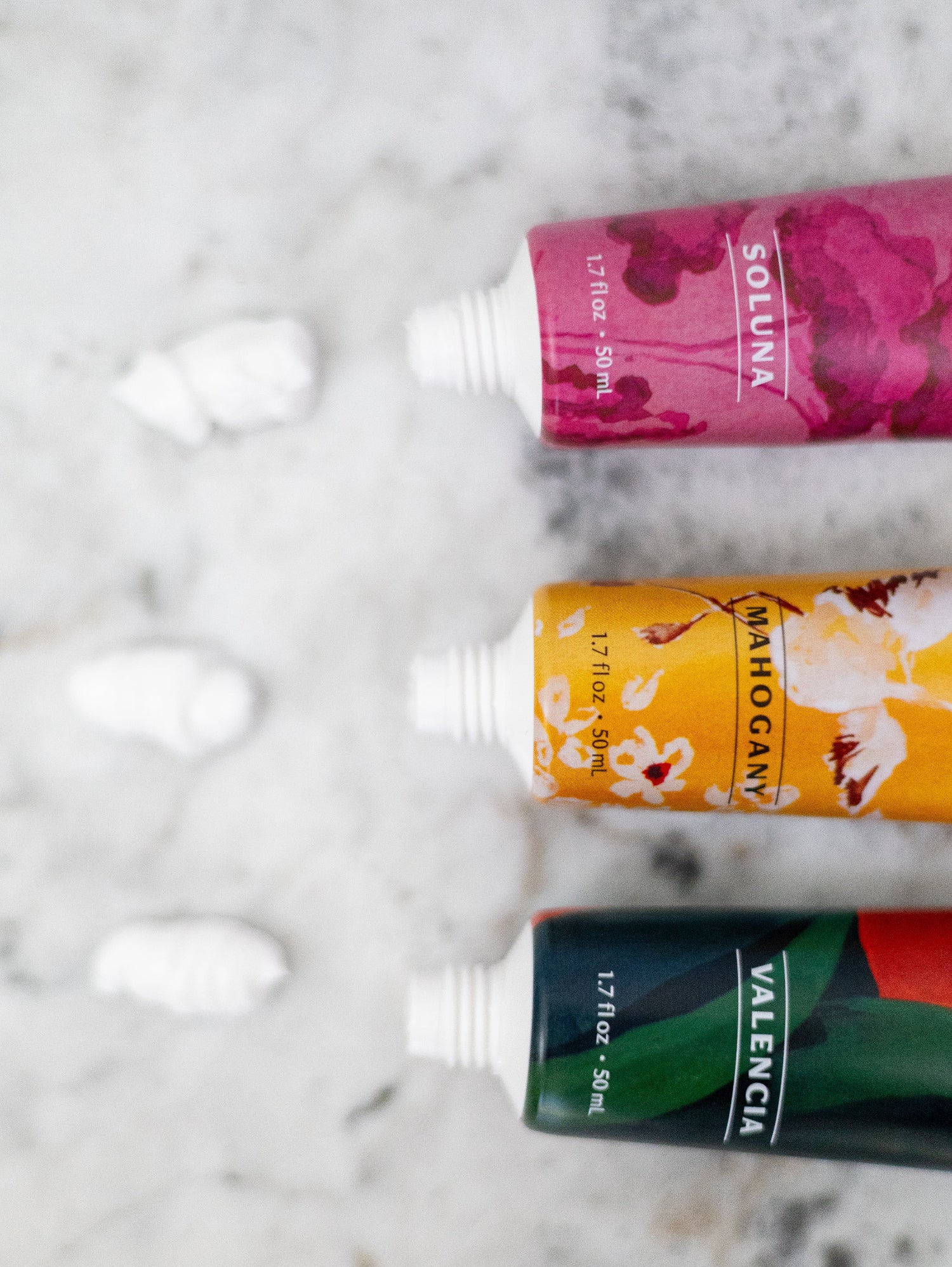 Three colorful hand cream tubes on a marble surface