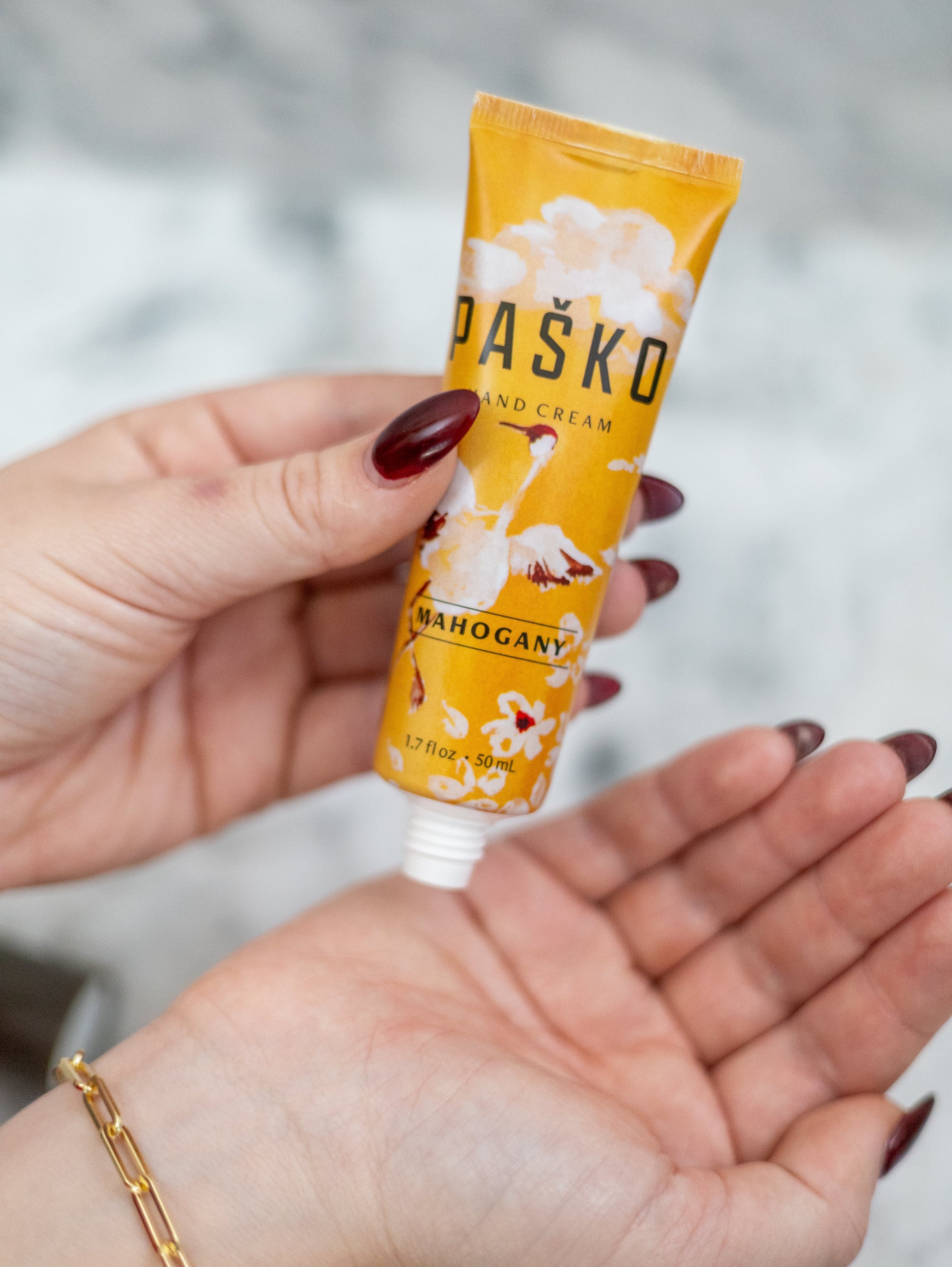 Hand holding a tube of Pasko Hand Cream with a blurred background
