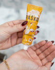 Hand holding a tube of Pasko Hand Cream with a blurred background
