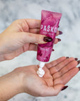 Hand holding a pink tube of Pasko Soluna hand cream with a blurred background