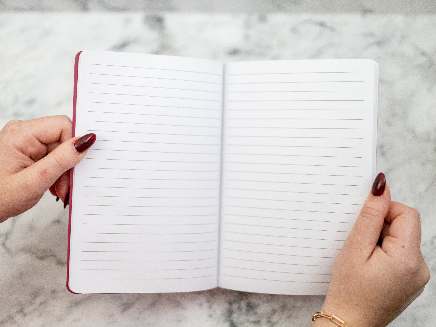 Open Pasko Valencia notebook held by hands on a marble surface